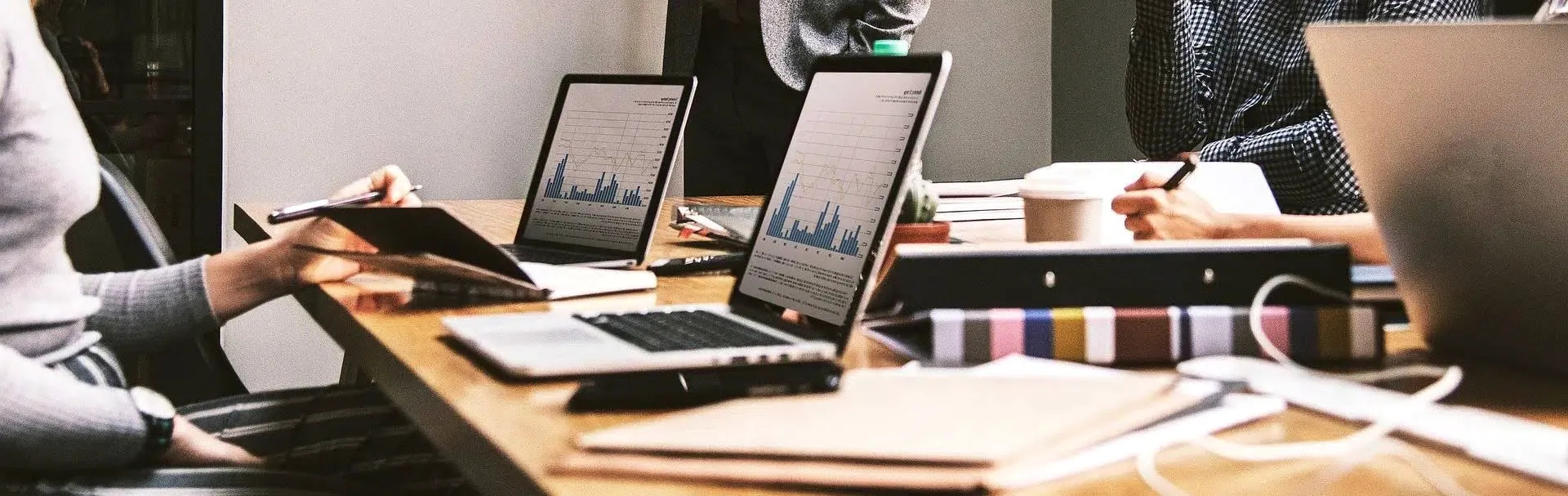 Equipo trabajando con portátiles alrededor de una mesa de oficina